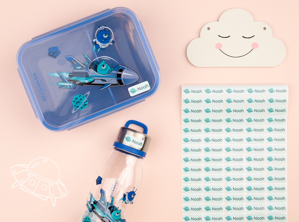Étiquettes nominatives : dois-je choisir des étiquettes autocollantes ou thermocollantes? 1 Boîte à lunch bleue, gourde et étiquettes autocollantes au design spatial