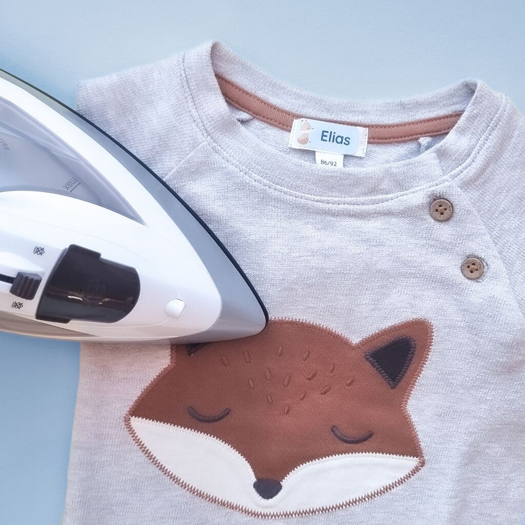 Application d’une étiquette thermocollante sur un sweat pour enfant
