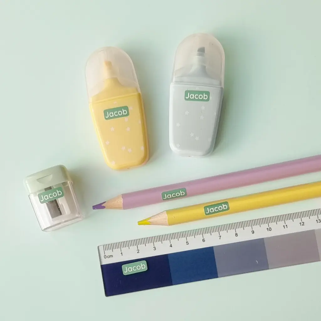 Étiquettes nominatives sur fournitures scolaires colorées.