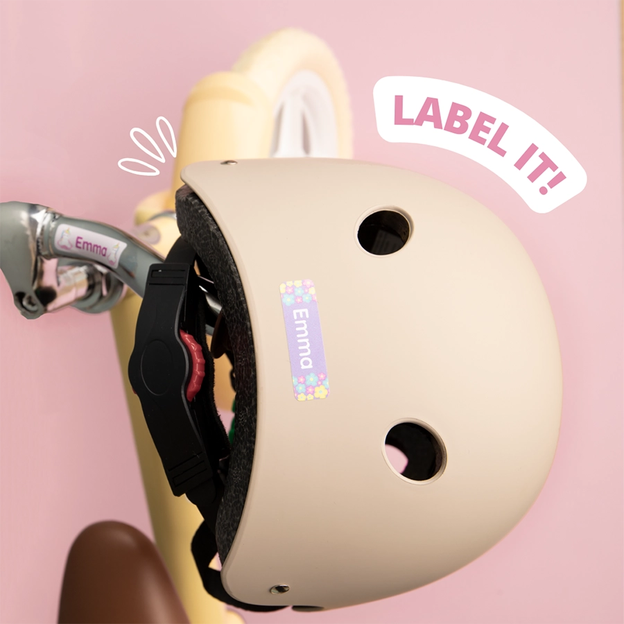Casque beige avec étiquette nominative personnalisée sur un vélo enfant.