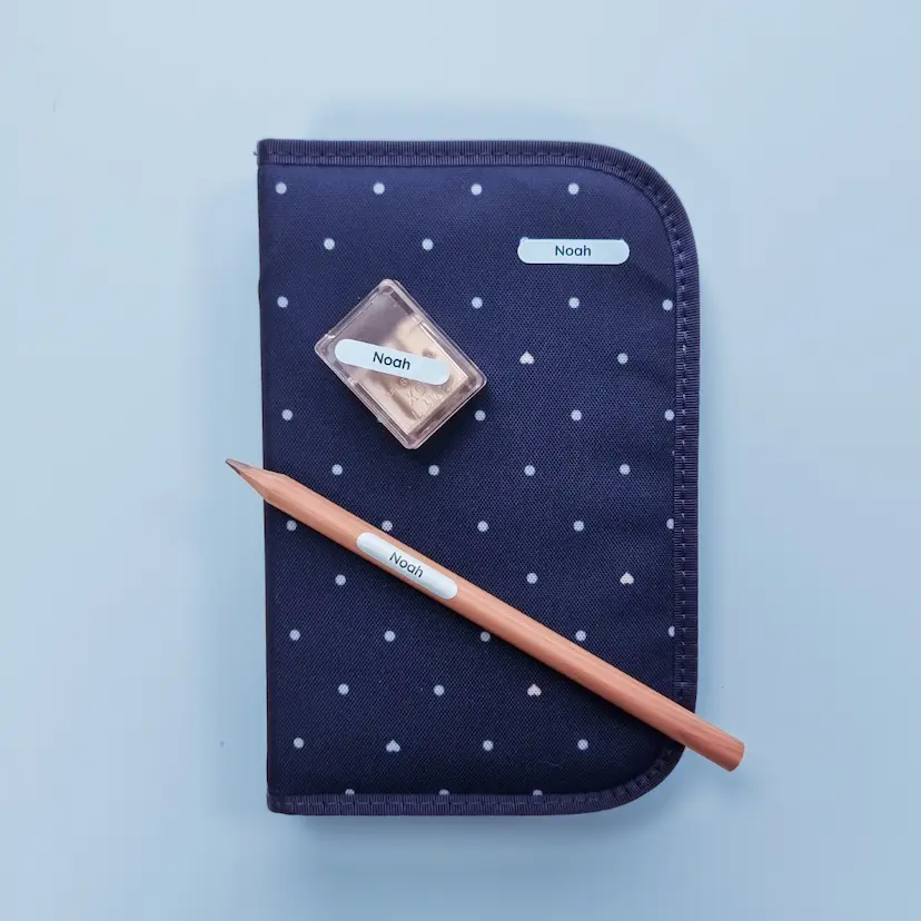 Étiquettes nominatives sur une trousse, un crayon et un taille-crayon.