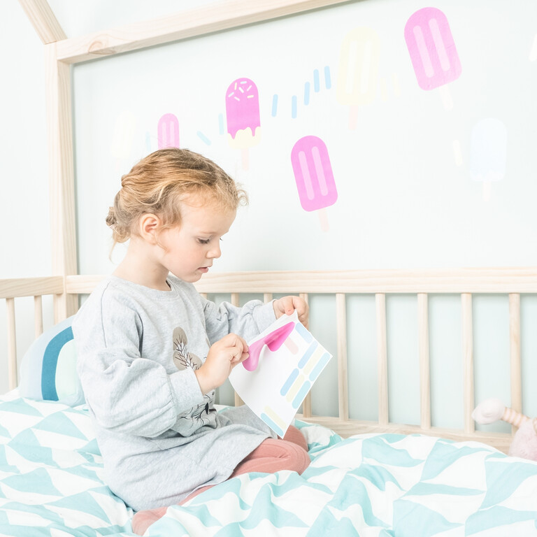 Fille collant des stickers muraux bâtonnets de glace sur le mur